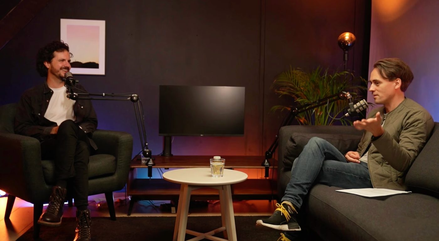 A guest interview filmed in a warm-toned lounge set