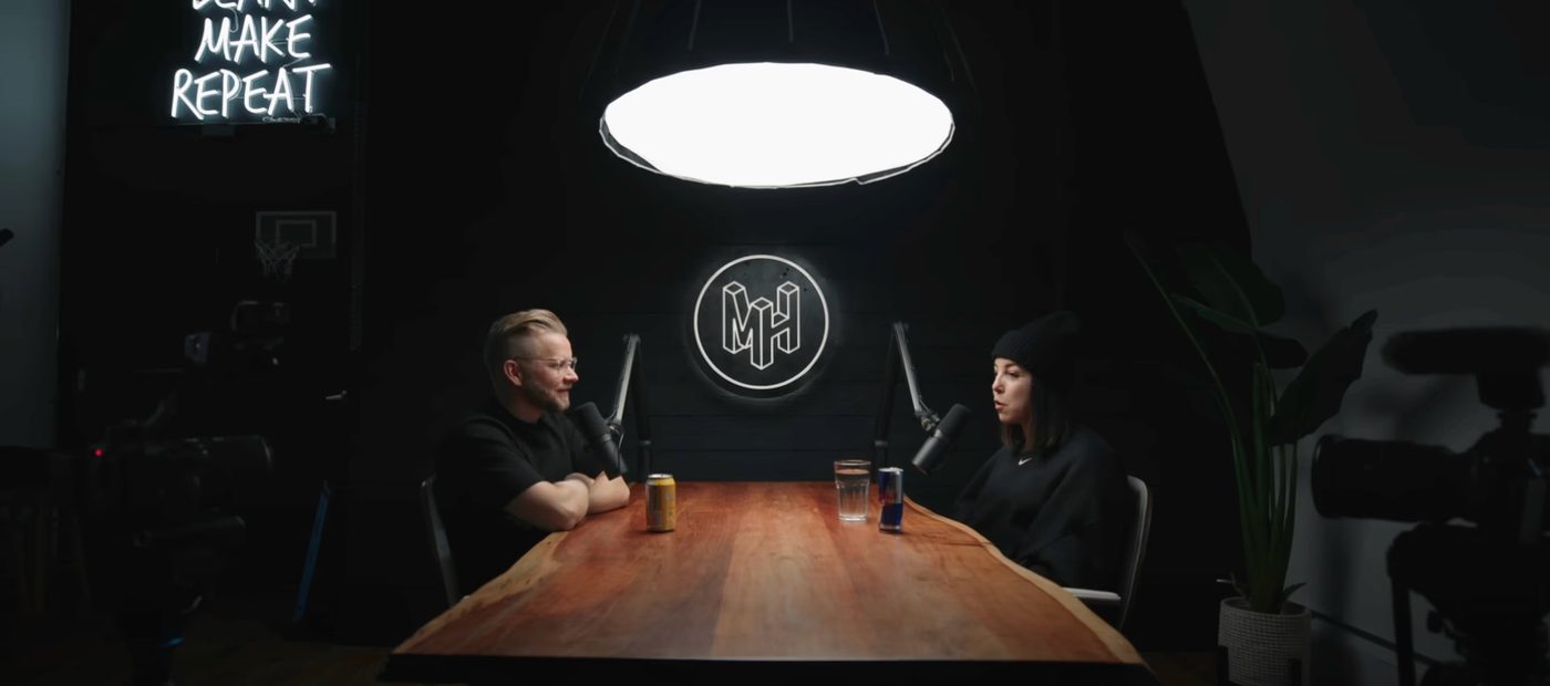 Two hosts filming under a single overhead light